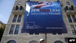 An Israeli youth walks past a poster welcoming and supporting US President Donald Trump in downtown Jerusalem, on May 19, 2017.