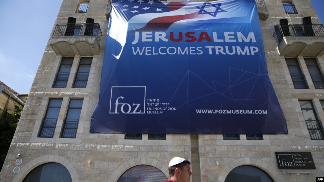 An Israeli youth walks past a poster welcoming and supporting US President Donald Trump in downtown Jerusalem, on May 19, 2017.