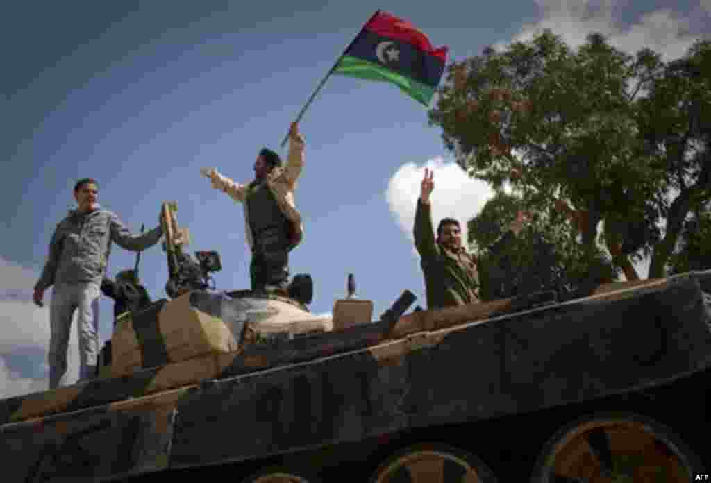 Libyan rebels celebrate on a captured tank in the outskirts of Benghazi, eastern Libya, Sunday, March 20, 2011. The U.S. military said 112 Tomahawk cruise missiles were fired from American and British ships and submarines at more than 20 coastal targets t