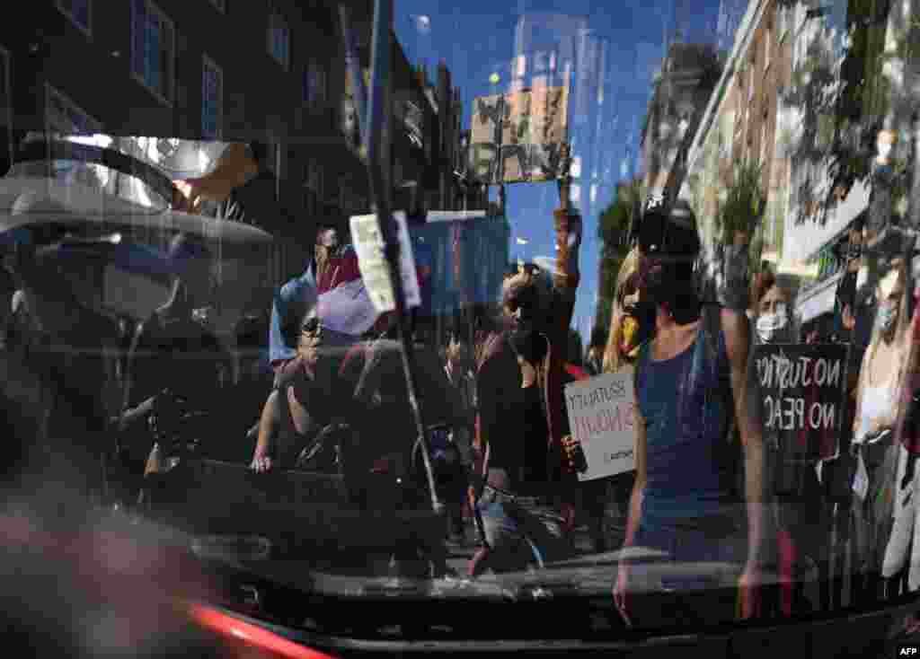 Demonstrators are reflected in the windscreen as they stop a bus blocking the street in Sloane Square in London on May 31, 2020 after marching on the US embassy to protest the death of George Floyd.