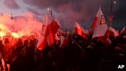 FILE - Demonstrators burn flares and wave Polish flags during the annual march to commemorate Poland's National Independence Day in Warsaw, Poland, Nov. 11, 2017.