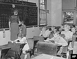 In this photo of an old, one-room classroom in Grundy, Iowa, the 7-year-old boy getting help at the blackboard is the only second-grader in the class.