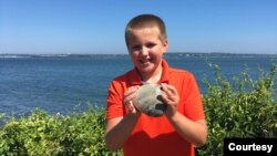 Cooper Monaco holds a giant quahog that weighs nearly 1 kilogram. It was donated to the University of Rhode Island's Marine Science Research Facility. (Todd McLeish/University of Rhode Island)