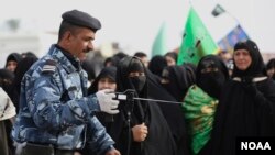 An Iraqi policeman uses a bomb detector to search Shi'ite pilgrims heading to the Shi'ite holy city of Kerbala, 80 kilometers (50 miles) south of Baghdad, Dec. 10, 2014. 