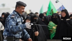 An Iraqi policeman uses a bomb detector to search Shi'ite pilgrims heading to the Shi'ite holy city of Karbala, 80 kilometers (50 miles) south of Baghdad, Iraq, Dec. 10, 2014. 