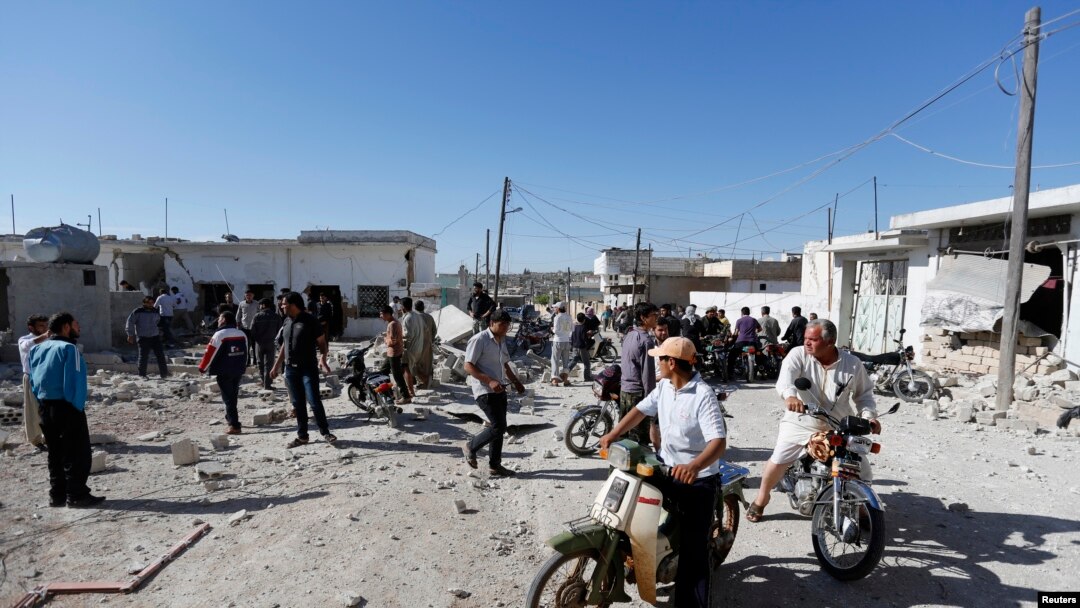 Warga berkerumun di lokasi yang terkena serangan yang oleh para aktivis disebut bom barel yang dilancarkan oleh pasukan setia Presiden Bashar al-Assad di desa al-Letmana, provinsi Hama (1/5).