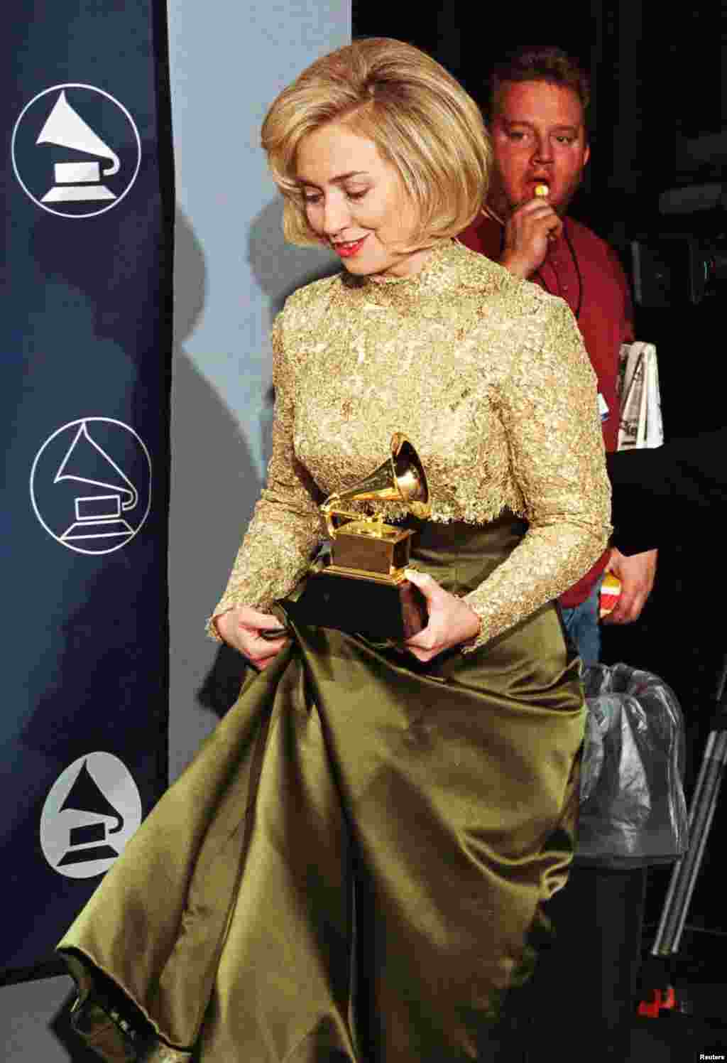 First Lady Hillary Rodham Clinton lifts the hem of her Oscar de la Renta gown backstage, after winning a Grammy in the Best Spoken Word catagory for &quot;It Takes a Village&quot; at the 39th Grammy Awards at Madison Square Garden in New York, February 26, 1997. 