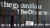 FILE - A woman walks past the offices of The Guardian newspaper in central London, August 20, 2013.