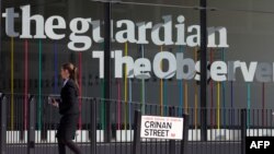 FILE - A woman walks past the offices of The Guardian newspaper in central London, August 20, 2013.