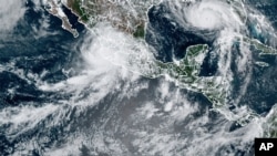 This image provided by the National Oceanic and Atmospheric Administration (NOAA) shows severe weather systems, Hurricane Nora, upper left, and Hurricane Ida, upper right, over the North American continent on Aug. 28, 2021.