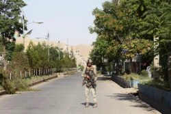 An Afghan security forces personnel stands guard along a road amid ongoing fighting with Taliban fighters in the western city of Qala-i- Naw, the capital of Badghis province, July 8, 2021.