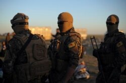 FILE - Fighters of Syrian Democratic Forces (SDF) are seen standing near the village of Baghuz, Deir al-Zour province, Syria, March 1, 2019.