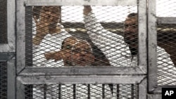 Leader of Egypt's Muslim Brotherhood Mohammed Badie, bottom center, and senior Brotherhood figurer Salah Soltan, right, gesture, during an appearance at a courtroom in Cairo, April 1, 2014. 