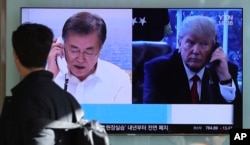 FILE - A man walks by a TV screen showing a local news program reporting about North Korea's missile launch with an images of U.S. President Donald Trump and South Korean President Moon Jae-in at the Seoul Railway Station in Seoul, South Korea, Dec. 1, 2017.