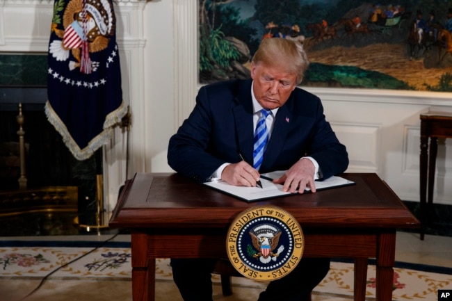 FILE - President Donald Trump signs a Presidential Memorandum on the Iran nuclear deal from the Diplomatic Reception Room of the White House, May 8, 2018.