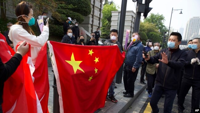 武汉保安试图驱散在一个公园外举着国旗和花束祭奠新冠疫情死难者的人群。（2020年4月4日）