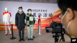 2021 年 12 月 9 日，在北京郵電大學舉行的一場活動中，學生們與奧運聖火和穿著奧運火炬傳遞制服的人體模型合影。