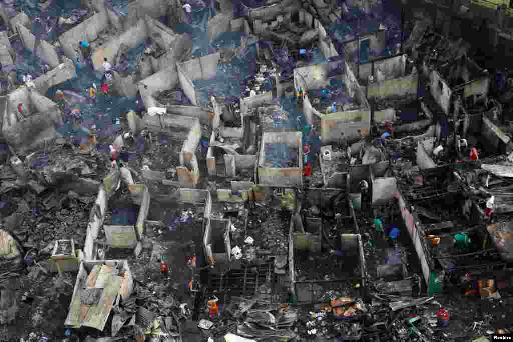Residents sift through the ruins of their houses after a fire razed a squatter colony, in Quezon city, Metro Manila in the Philippines.