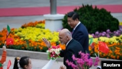 Afghanistan's President Ashraf Ghani Ahmadzai (L) waves to students as he and China's President Xi Jinping attend a welcoming ceremony outside the Great Hall of the People, in Beijing, Oct. 28, 2014.
