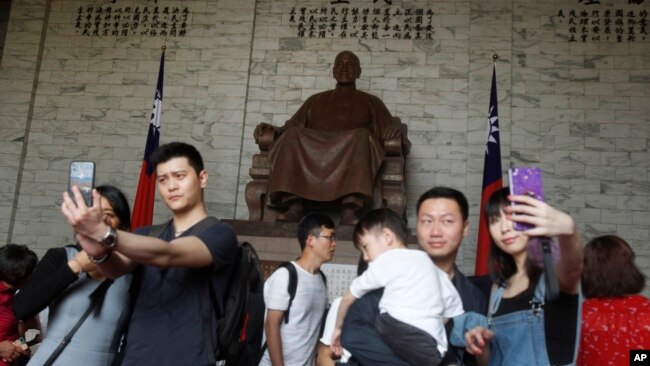 中国游客在台北中正纪念堂蒋介石铜像前摆姿势拍照。(2019年4月4日)