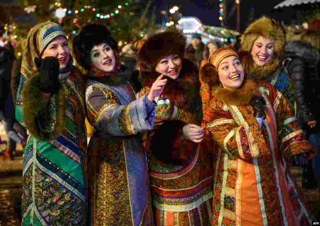 Women in traditional costumes entertain the visitors at the Christmas market on the Red Square in Moscow, Russia.