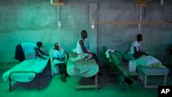 The daughter of 84-year-old Armant Germain replaces the sheets on her bed, in the cholera ward at a hospital in Les Cayes Haiti, Oct. 11, 2016. 