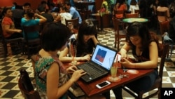 Three young Vietnamese girls use a laptop and smart phones to go online at a cafe in Ha Noi, Viet Nam Wednesday, May 14, 2013. (AP Photo/Na Son Nguyen)