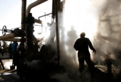 Seorang pekerja memperbaiki bagian dari unit kilang minyak Teheran, di Teheran, Iran.