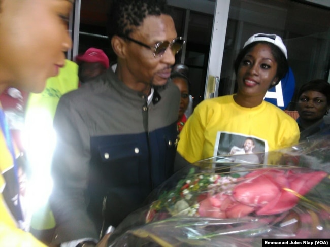 De retour au Cameroun, Rigobert Song reçoit un bouquet de fleurs à sa descente d'avion à l'aéroport international de Yaoundé Nsimalen, 1er avril 2017. (VOA/Emmanuel Jules Ntap)