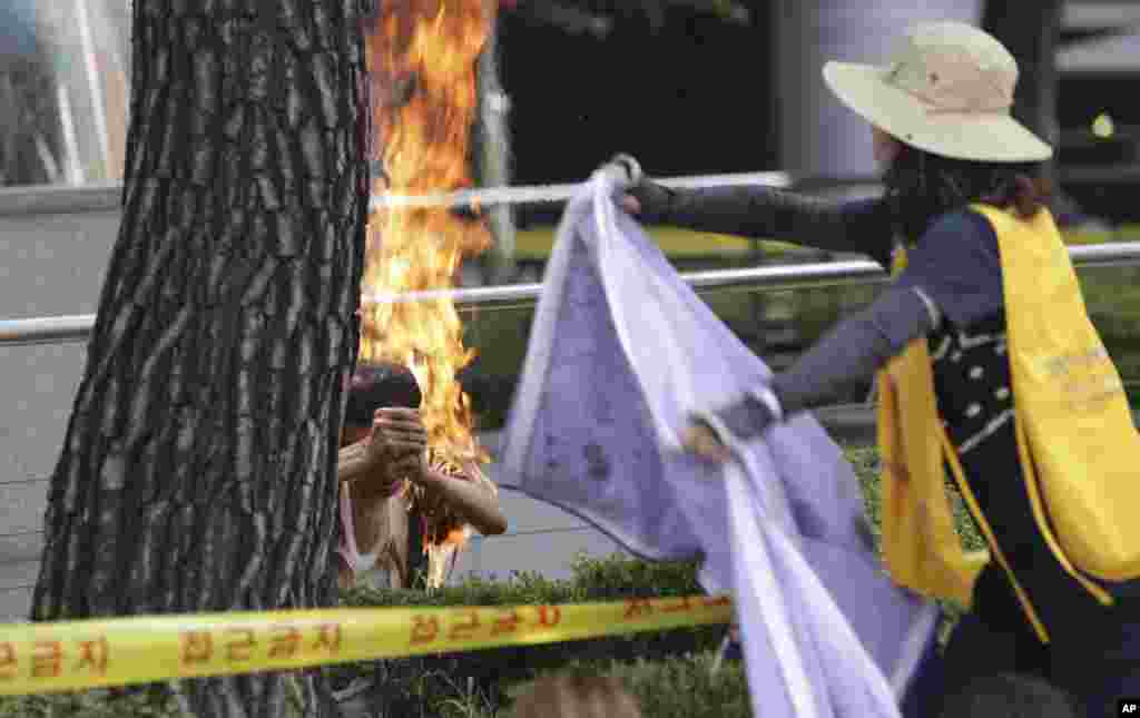 A South Korean man, left, sets himself on fire as a woman tries to extinguish him during an anti-Japan rally demanding full compensation and an apology for wartime sex slaves from the Japanese government in front of the Japanese Embassy in Seoul.