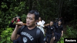 Members of a police forensic team carry a body bag with human remains dug from the grave near the abandoned human trafficking camp in the jungle close the Thailand border at Bukit Wang Burma in northern Malaysia May 27, 2015. Malaysian police forensic tea