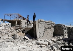 FILE - Men inspect a damaged house in Busra al-Harir, near Deraa, Syria, March 13, 2018. Russian jets struck the opposition-held town on June 24, 2018, opposition sources said.