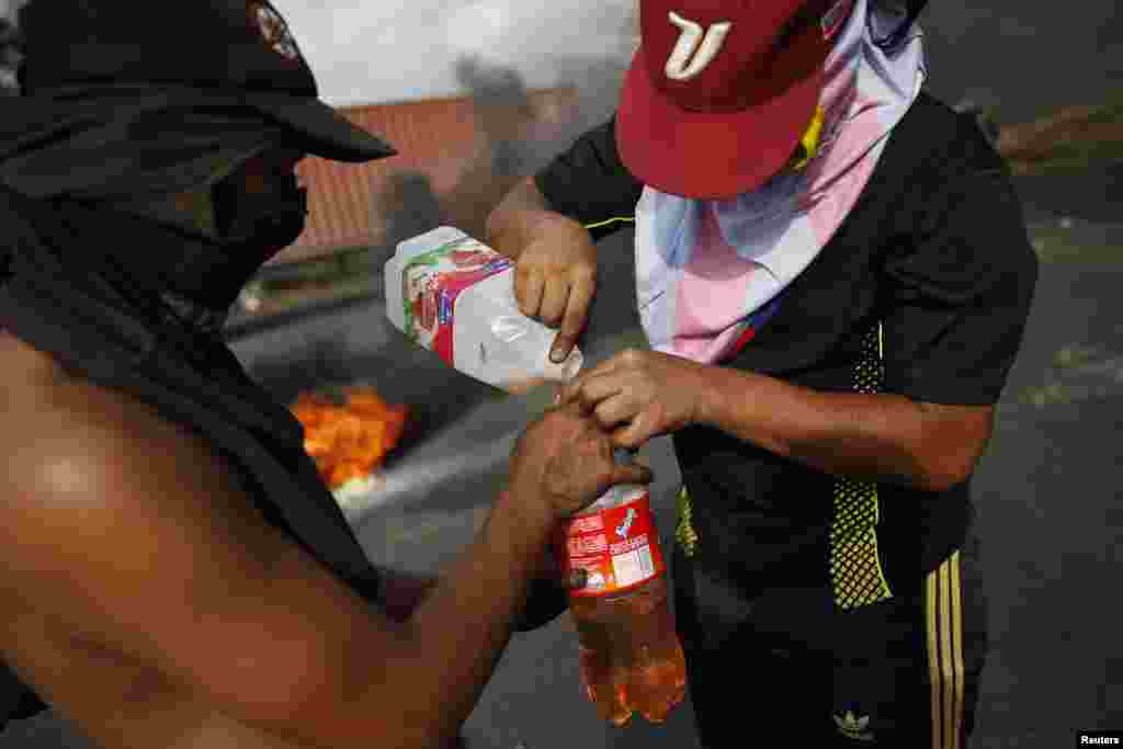 Para demonstran mengisi botol dengan bensin dalam protes melawan pemerintahan Presiden Nicolas Maduro di San Cristobal, sekitar 660 kilometer barat daya Caracas (26/2).&nbsp;(Reuters/Carlos Garcia Rawlins)