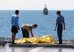 Awak kapal memeriksa tas berisi jenazah yang diyakini korban Penerbangan AirAsia 8501 di geladak kapal TNI AL KRI Banda Aceh, di Laut Jawa, Jumat 23 Januari 2015. (Foto: AP)