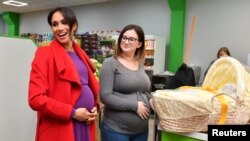 Meghan, Duchess of Sussex, memberikan sebuah keranjang Angela Midgley sebuah keranjang bayi di sebuah supermarket warga dan komunitas di Birkenhead, di Inggris, 14 Januari 2019. 
