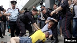 Policemen break up a fight between a gay rights activist and an anti-gay rights activist (in yellow) during a protest against a proposed new law termed by the lower house of Parliament, as "against advocating the rejection of traditional family values" in central Moscow June 11, 2013.