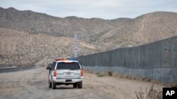 FILE - A U.S. Border Patrol agent drives near the U.S.-Mexico border fence in Sunland Park, New Mexico, Jan. 4, 2016. 