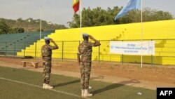 Des Casques bleus de la Mission des Nations Unies au Mali (MINUSMA) saluent les drapeaux de l'ONU et du Mali au stade Mamadou Konaté N'tomikorobougou à Bamako, Mali, 29 mai 2015.