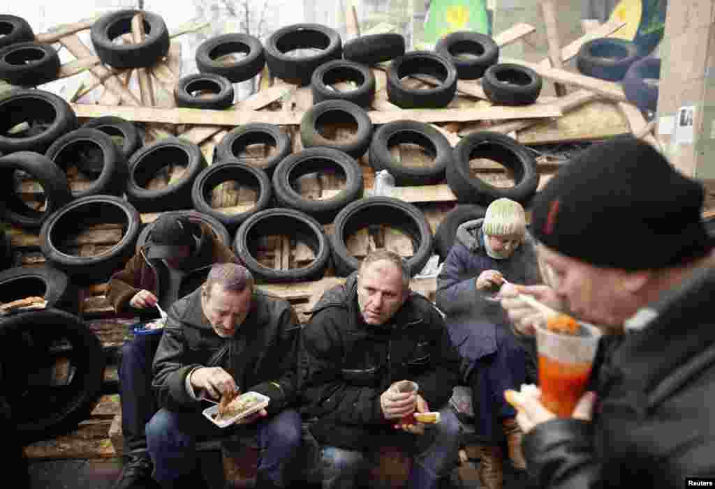 Pro-European integration protesters eat free meals near a barricade during a rally in Independence Square in Kiev, Dec. 16, 2013. 