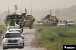 FILE - Kurdish fighters from the People's Protection Units (YPG) head a convoy of U.S military vehicles in the town of Darbasiya next to the Turkish border, Syria, April 28, 2017.