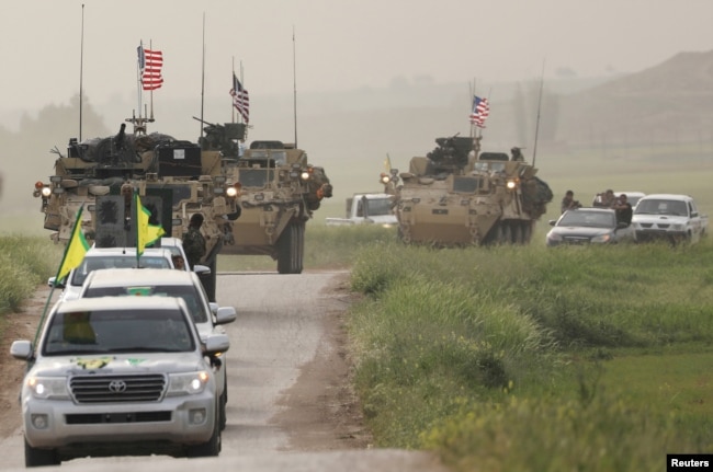 FILE - Kurdish fighters from the People's Protection Units (YPG) head a convoy of U.S military vehicles in the town of Darbasiya next to the Turkish border, Syria, April 28, 2017.