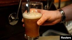 FILE - A barman pulls a pint of beer in a pub in Liverpool, northern England.