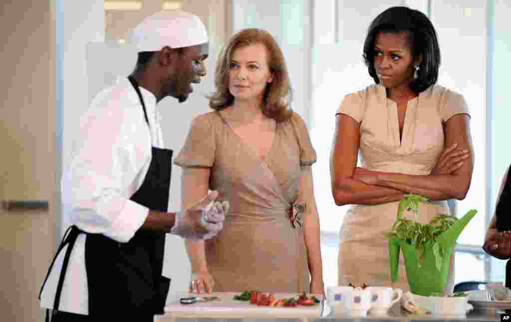 Valerie Trierweiler, partner of French President Francois Hollande, and first lady Michelle Obama watch a student explain the making of a meal during a tour of the Gary Corner Youth Center in Chicago. (AP)
