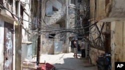 A tangle of electrical wires and water pipes, and anti-Semitic graffiti line the alleyways of the Shatila refugee camp in Lebanon, 31 Aug 2010