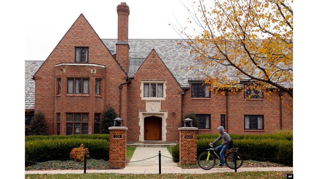 FILE – In this Nov. 9, 2017, photo, a bicyclist rides past Penn State's shuttered Beta Theta Pi fraternity house in State College, Pa. The parents of Penn State student Tim Piazza, 19, who died in a hazing ritual while pledging for Beta Theta Pi, reached a settlement in September 2018 with the fraternity's national organization that provides for reforms. The Beta Theta Pi chapter was permanently banned by the university.