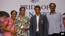 India’s P.V. Sindhu, second left, who won one of India's two medals at the Rio de Janeiro Olympics poses with her coach Pullela Gopichand, second right, mother, P. Vijaya, left, and father, P.V. Ramana, right, during their reception at the Gopichand Acade