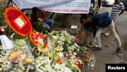 People place flowers at a makeshift memorial near the site, to pay tribute to the victims of the attack on the Holey Artisan Bakery and the O'Kitchen Restaurant, in Dhaka, Bangladesh, July 5, 2016. REUTERS/Adnan Abidi 