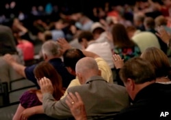 People pray during the Southern Baptist Convention annual meeting, June 13, 2017, in Phoenix.