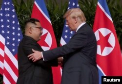 미북 정상회담에 앞서 12일 도널드 트럼프 미국 대통령(오른쪽)과 김정은 위원장이 만나 인사를 나누고 있다.