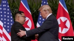 미북 정상회담에 앞서 12일 도널드 트럼프 미국 대통령(오른쪽)과 김정은 위원장이 만나 인사를 나누고 있다.